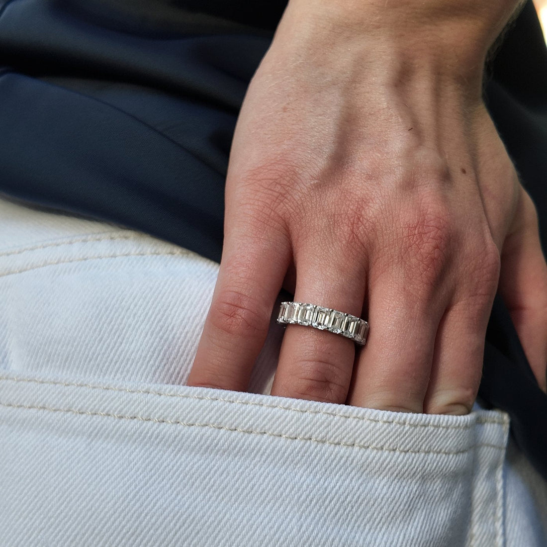 A hand wearing a diamond eternity band
