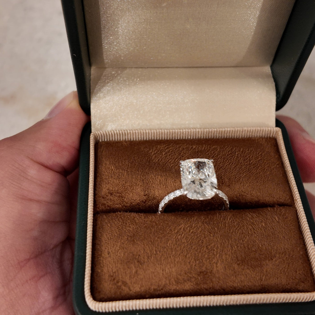An engagement ring in an open box, held in the hand at the Irdoja showroom