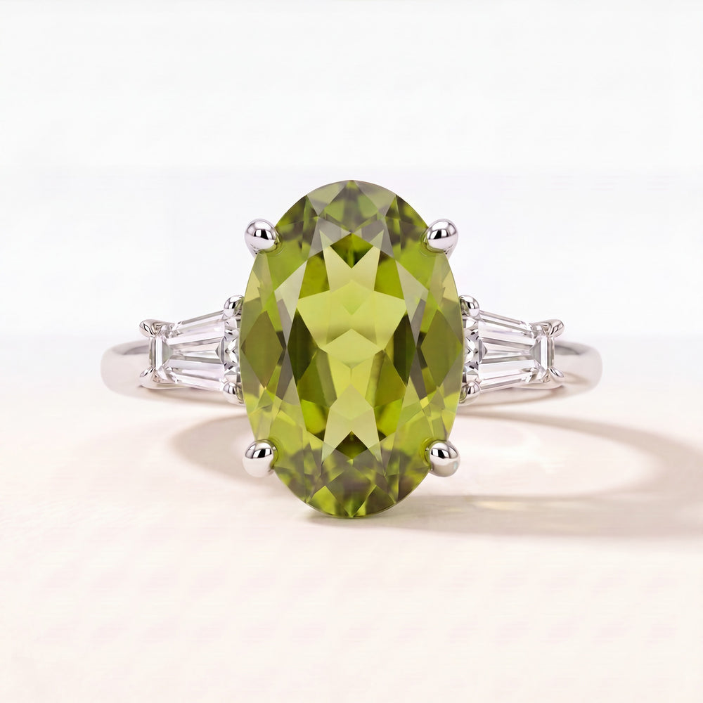 Oval peridot ring with tapered baguette diamond shoulders in platinum, studio view