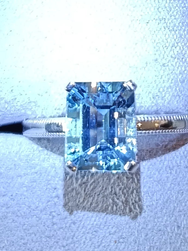 Emerald-cut aquamarine solitaire ring with milgrain detail in 14K gold by Irdoja Diamonds.