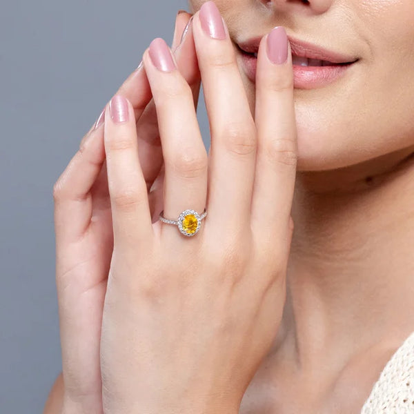 Prong-set oval yellow sapphire halo ring with diamond accents in 14k gold by Irdoja Diamonds.