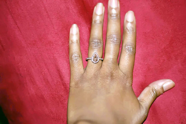 Prong-set pear morganite ring with diamond halo on a hand, featuring 14k gold band.