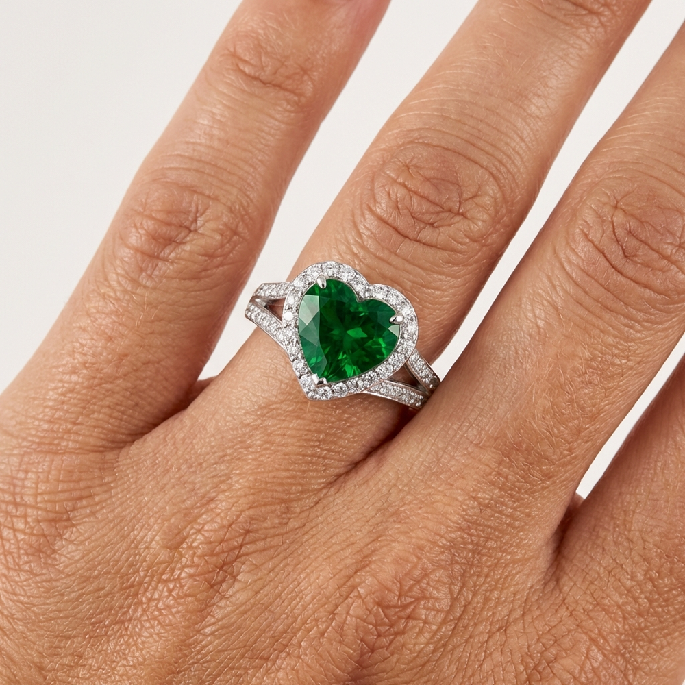 Heart-Shaped Lab Emerald Engagement Ring with Diamond Halo displayed on a hand, showcasing the vibrant green centerpiece and diamond accents.