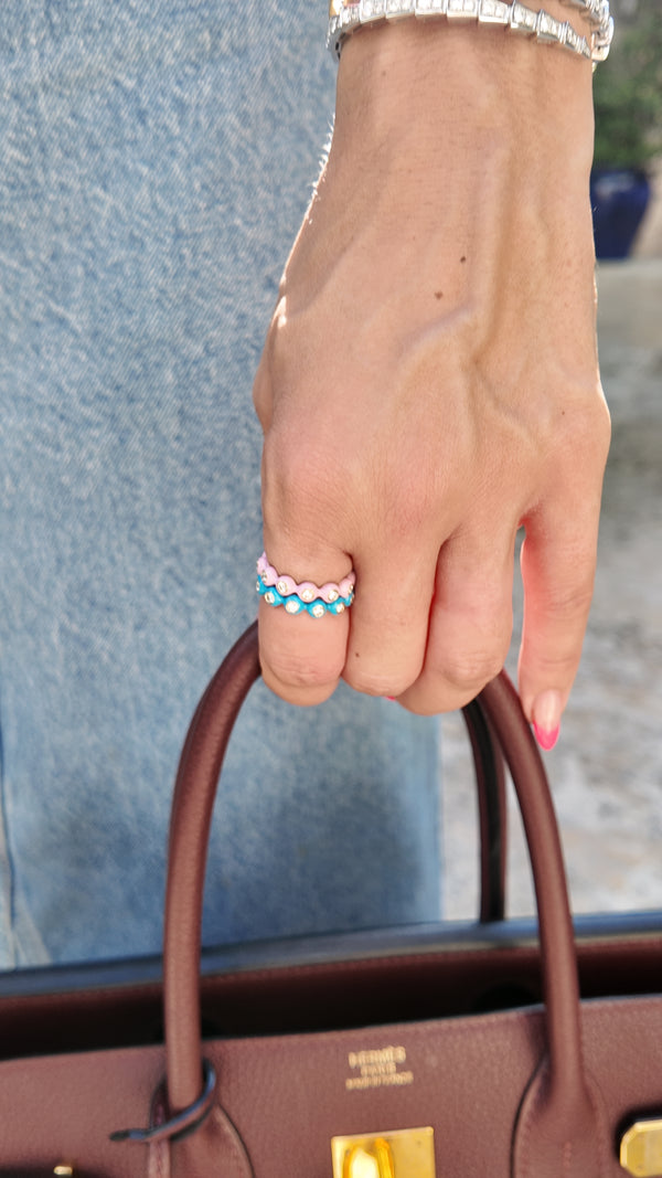 Two Irdoja Bubble bands worn together on one finger, pink and teal enamel, shown at everyday scale on the hand.