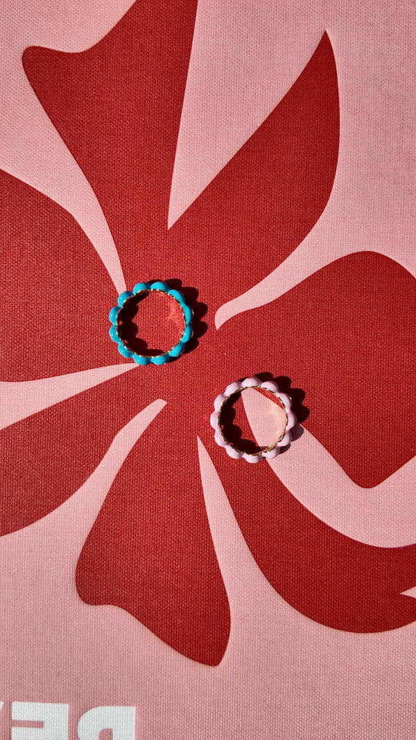 Two Irdoja Bubble bands, teal and pink, laid on a printed cover to show their scale.