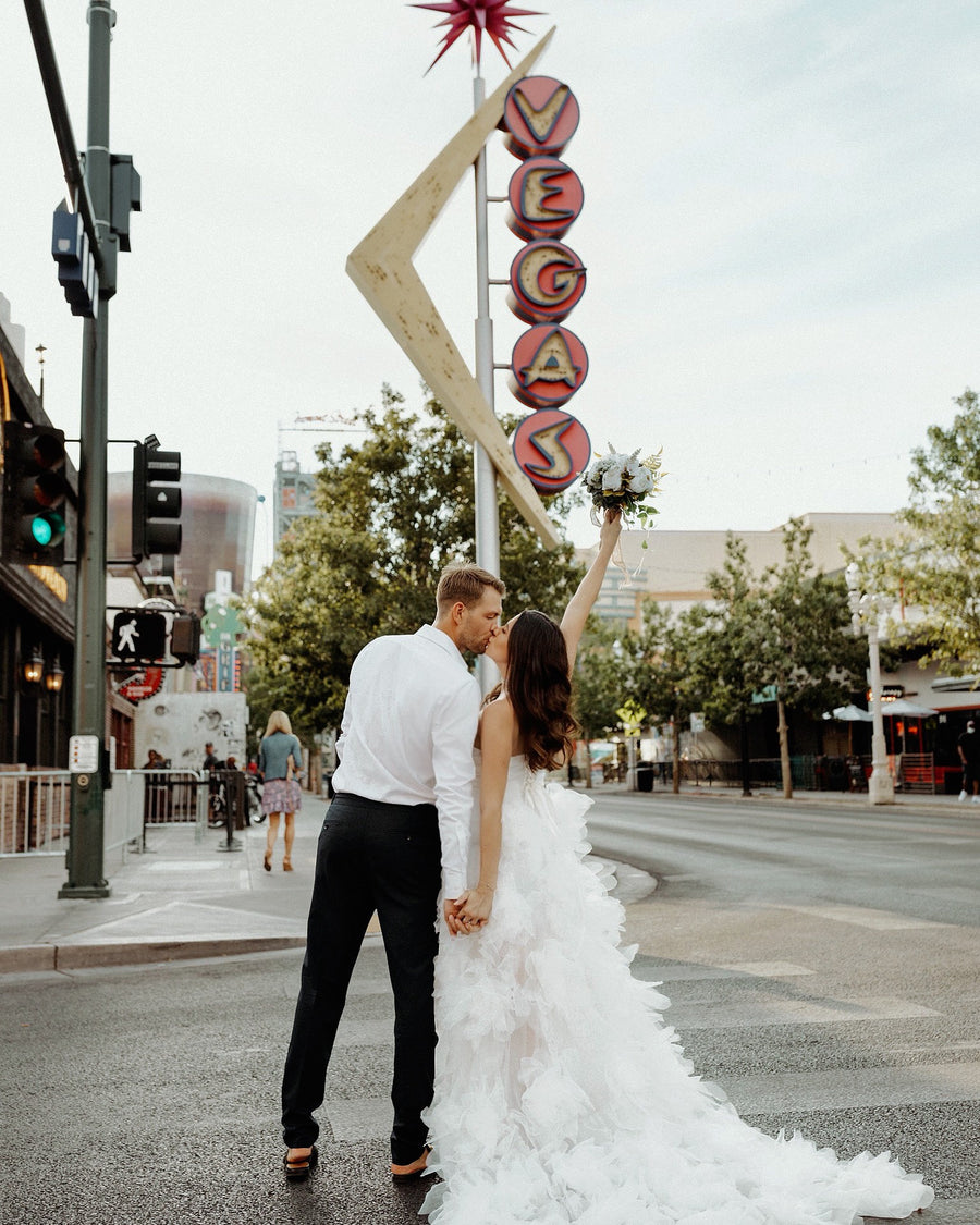 A bride and groom beneath a neon Vegas sign