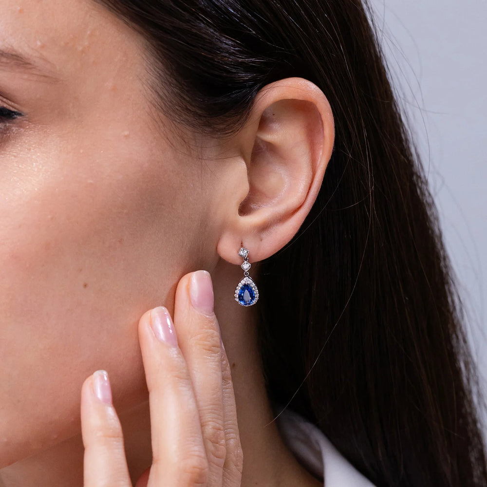 Pear blue sapphire drop earrings with diamond halo, set in 18K and 14K gold by Irdoja Diamonds.