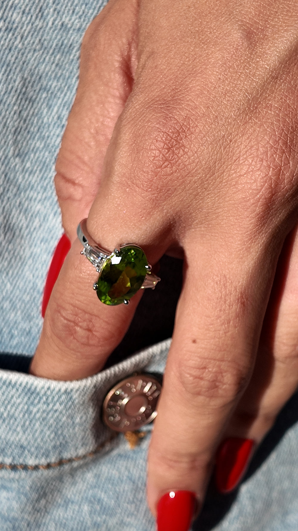 Oval peridot ring with tapered baguette diamond shoulders in platinum, studio view