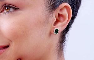 Lab-Grown Emerald-Cut Emerald Stud Earrings with Lab Diamond Halo worn by a model, showcasing vibrant green color.