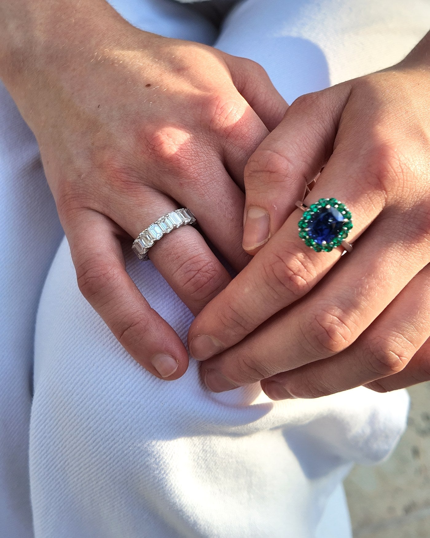 A blue sapphire in a green emerald halo, worn with a diamond eternity band