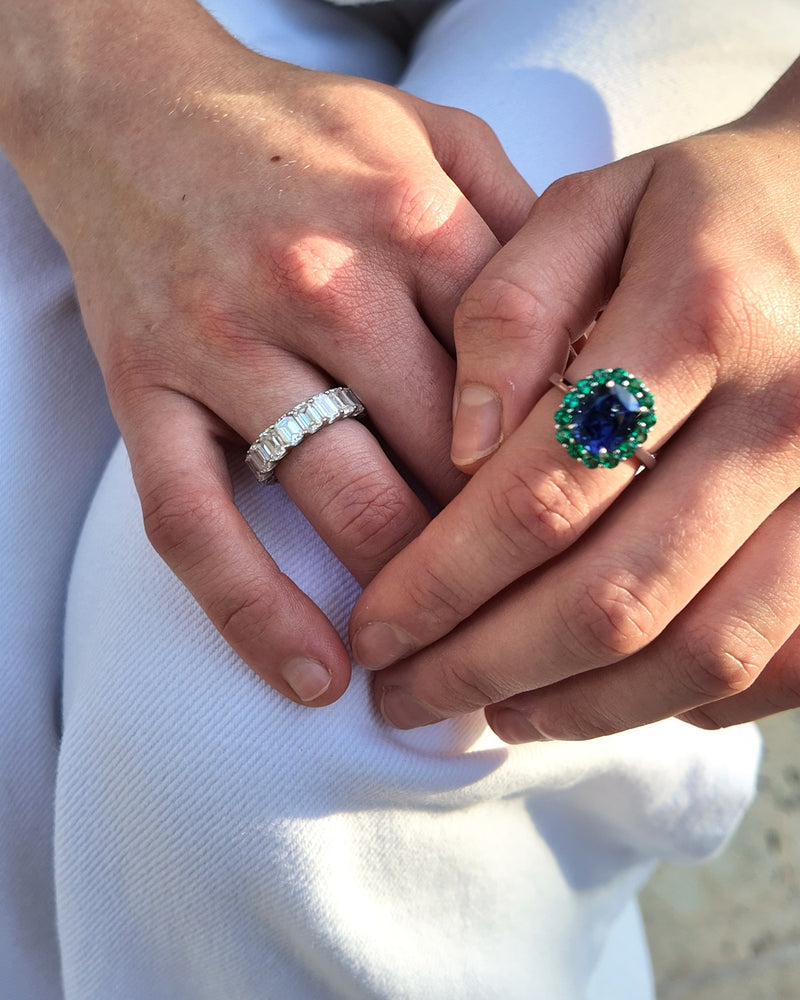A sapphire halo ring and an emerald-cut eternity band, worn
